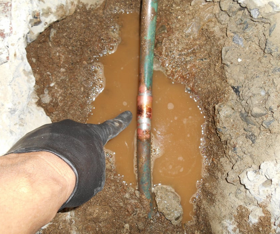 A plumber pointing to a leak using electronic equipment before hydrojetting.