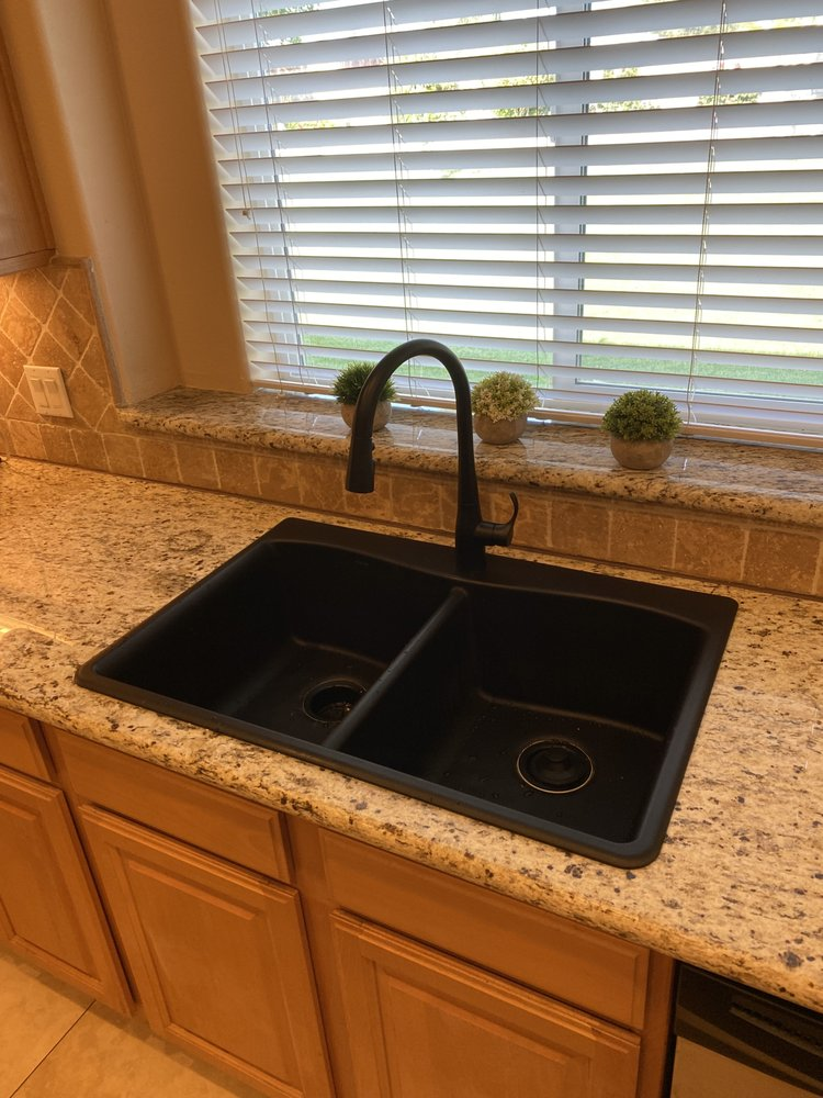 A clean kitchen sink with water draining slowly.