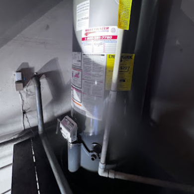 Close-up of a water heater in a residential setting, showcasing pipes and energy efficiency labels.