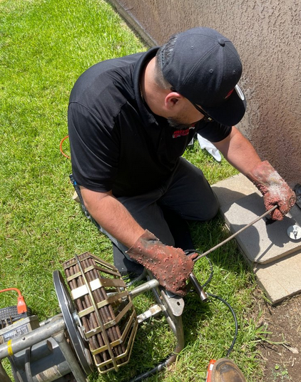 A plumber clearing clogs in a drain.