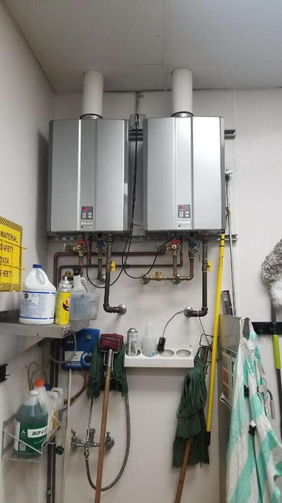 Two water heaters installed side by side in a residential utility room.