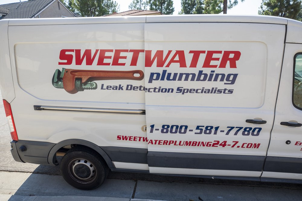 A Sweetwater Plumbing service van parked outside a home for water heater installation.