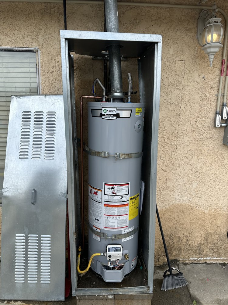 Plumber using tools to connect pipes during a water heater installation in a residential basement.