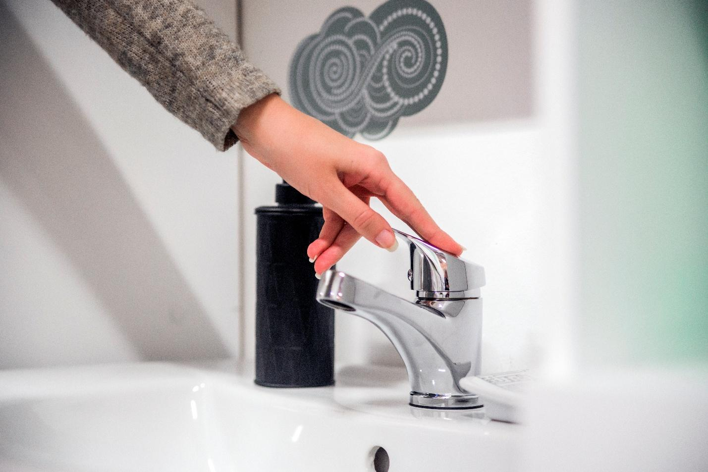 Person adjusting single-handle bathroom faucet