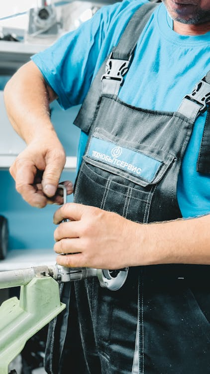 Plumber repairing an indoor pipe with a wrench in Ontario, CA.