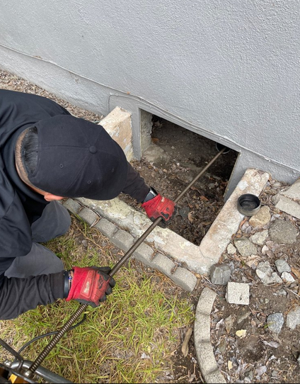 A plumber cleaning a drain.