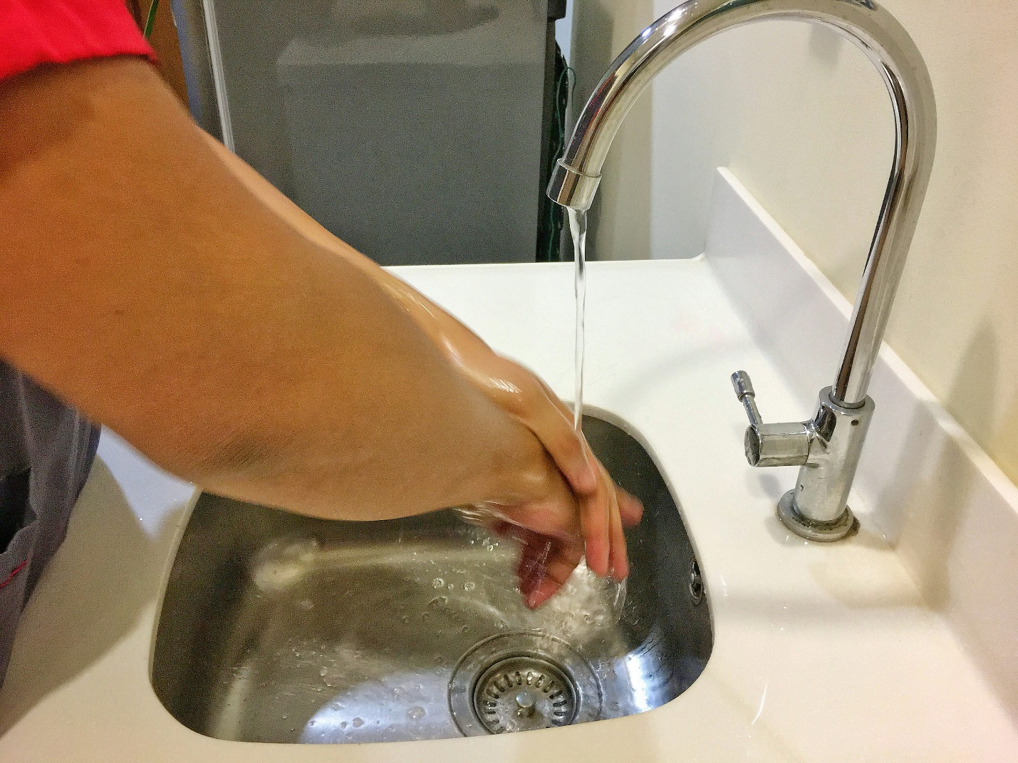 Person washing hands over a running faucet symbolizing functional home plumbing.
