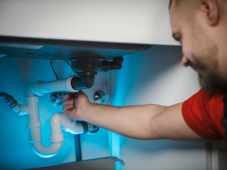 Ontario plumber repairing pipes under a sink, ensuring quick and reliable plumbing service.