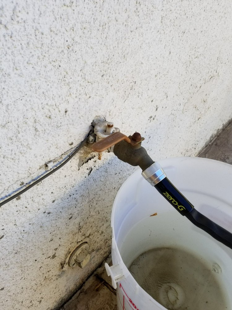 bucket placed under a leaking water pipe with a valve