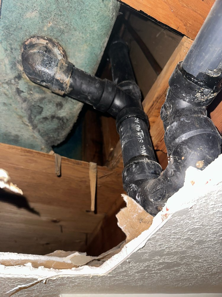old and crusty, black pipes leaking and causing water damage, leading to tearing down the wall