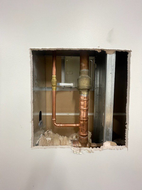 stainless steel water pipes fixed and repiped inside a white drywall