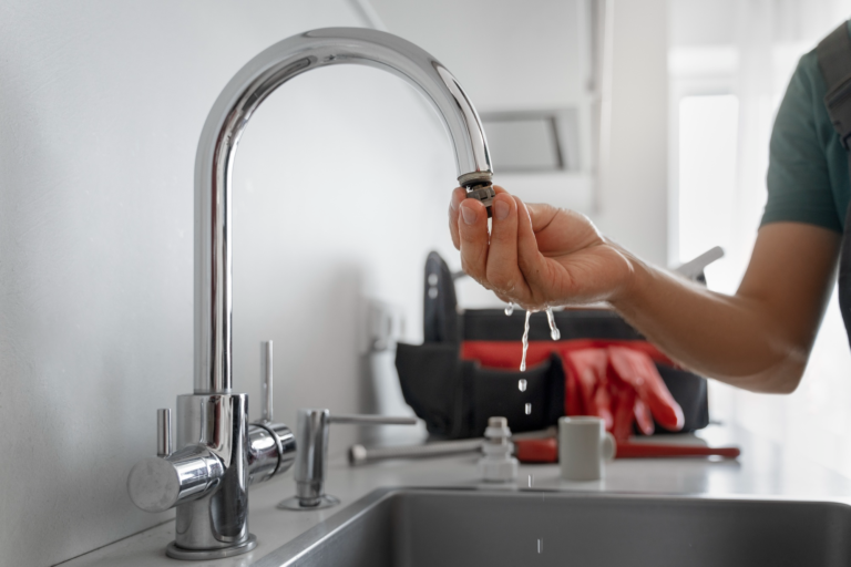 Plumber inspecting a kitchen faucet showing signs of low water pressure