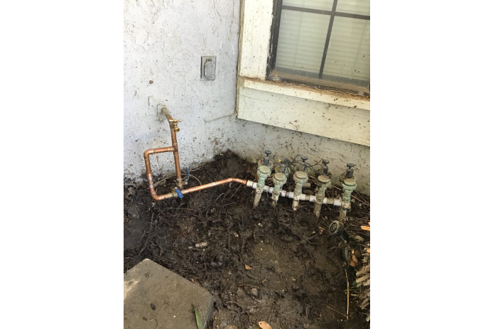Outdoor plumbing valves and pipes near the house foundation