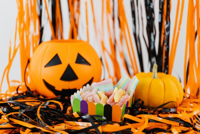 A glowing jack-o'-lantern surrounded by assorted Halloween candy.