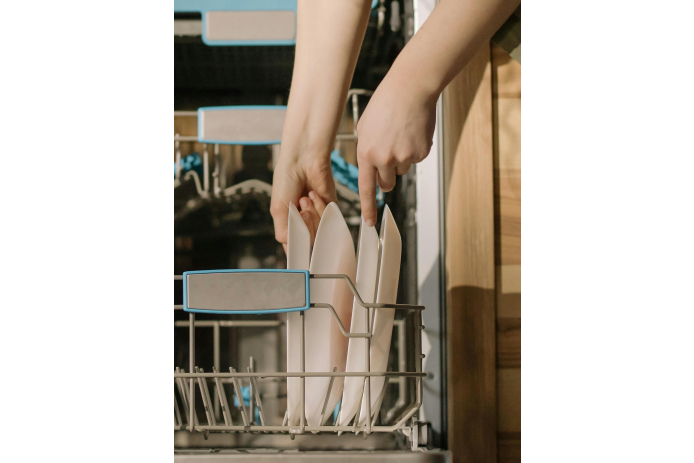 Person placing plates into a dishwasher.
