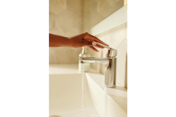 Person holding a faucet with running water.