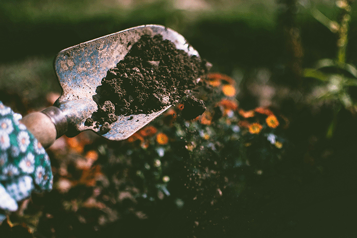 Person digging up soil with a garden shovel